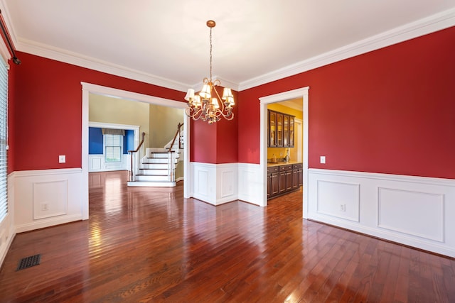 unfurnished dining area featuring crown molding, a chandelier, and dark hardwood / wood-style flooring