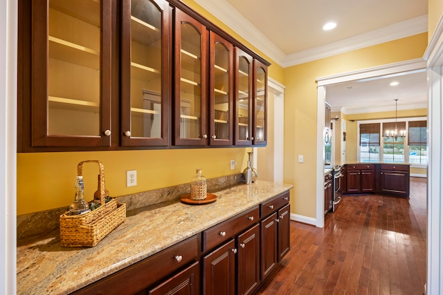 bar with an inviting chandelier, light stone countertops, pendant lighting, dark wood-type flooring, and ornamental molding