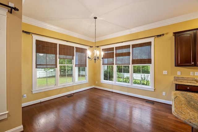 unfurnished dining area featuring dark wood-type flooring, ornamental molding, an inviting chandelier, and a healthy amount of sunlight