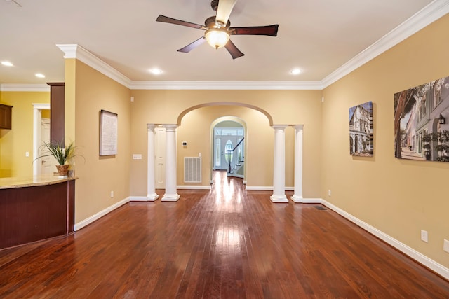 empty room featuring crown molding, dark hardwood / wood-style flooring, ornate columns, and ceiling fan