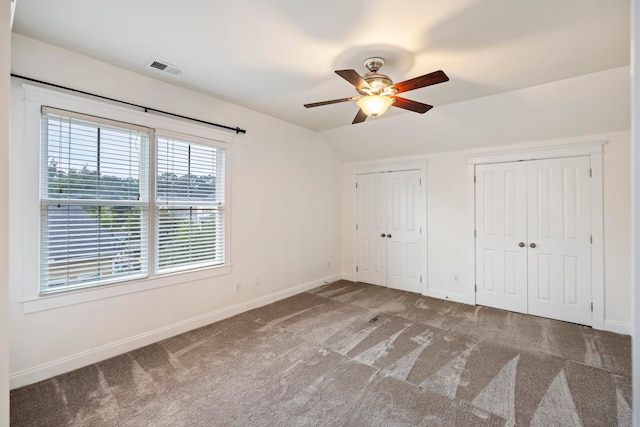 unfurnished bedroom featuring multiple closets, vaulted ceiling, ceiling fan, and carpet flooring