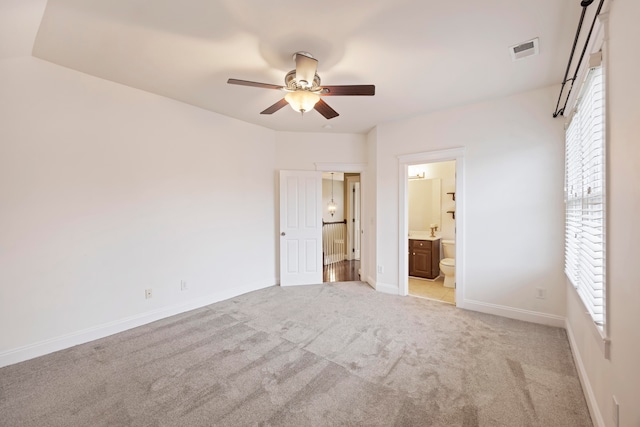 unfurnished bedroom featuring ceiling fan, connected bathroom, and light carpet