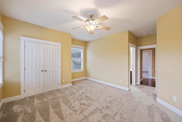 unfurnished bedroom featuring a closet, ceiling fan, and light colored carpet