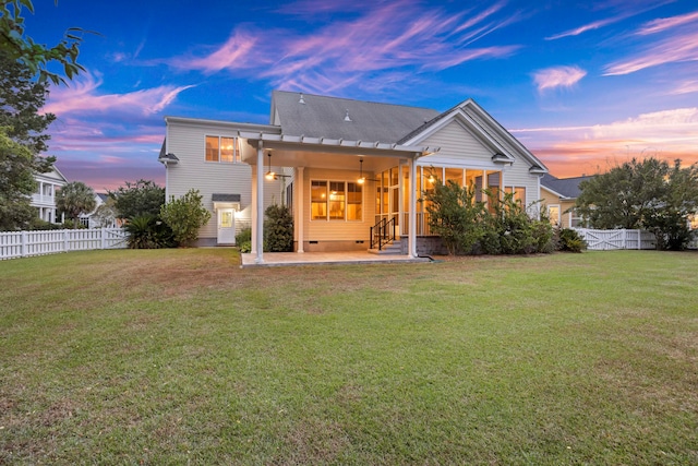 back house at dusk with a lawn and a patio