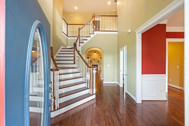 foyer entrance featuring ornamental molding, a towering ceiling, and dark hardwood / wood-style floors