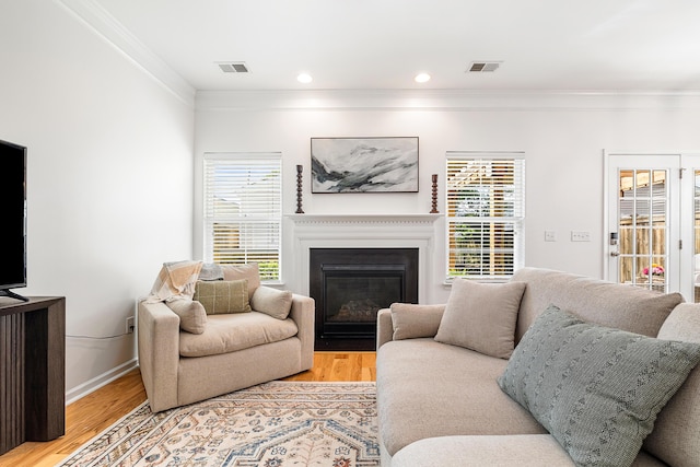 living area featuring crown molding, visible vents, and light wood finished floors
