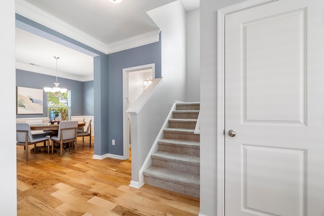 stairs with crown molding, baseboards, wood finished floors, and a chandelier
