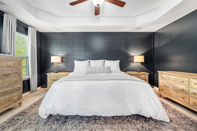 bedroom with carpet floors, a ceiling fan, and a tray ceiling