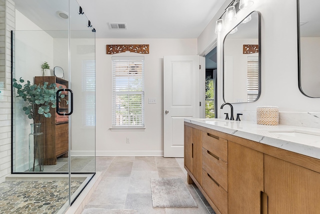 full bath with double vanity, visible vents, a shower stall, and a sink