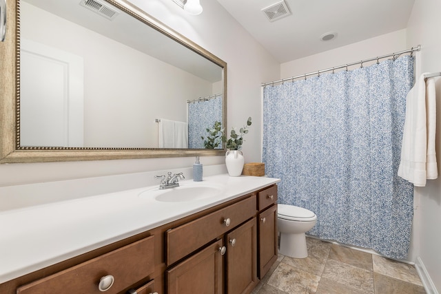 bathroom featuring visible vents, stone finish flooring, toilet, and vanity