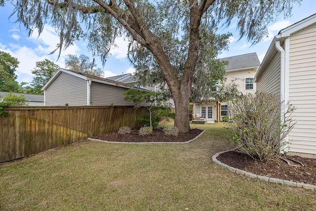 view of yard featuring fence and french doors