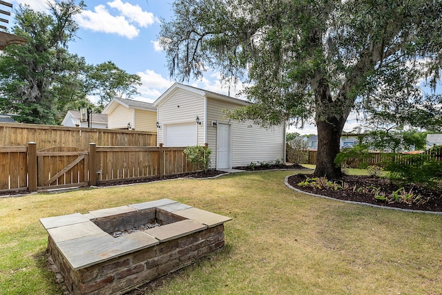 view of yard featuring fence, an outbuilding, an outdoor fire pit, and a garage