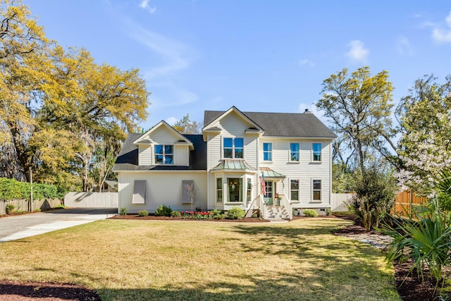 view of front of home featuring roof with shingles, fence, a front yard, and concrete driveway