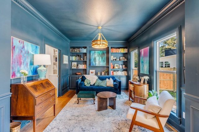 sitting room with a notable chandelier, built in features, wood finished floors, visible vents, and ornamental molding