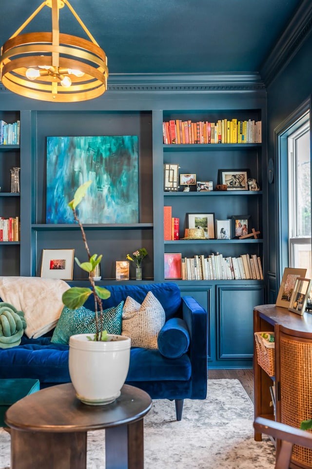 living area featuring crown molding, built in shelves, and wood finished floors