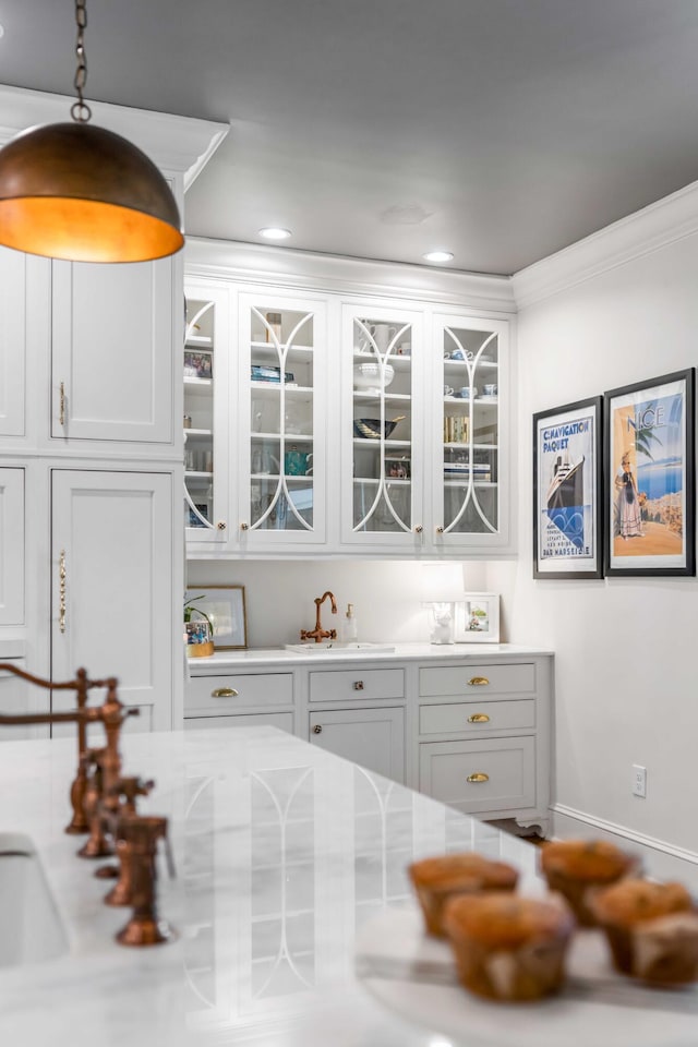 interior space with pendant lighting, a sink, baseboards, ornamental molding, and recessed lighting