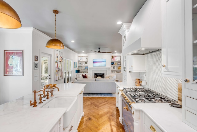 kitchen with a ceiling fan, light countertops, premium range hood, white cabinetry, and gas range oven