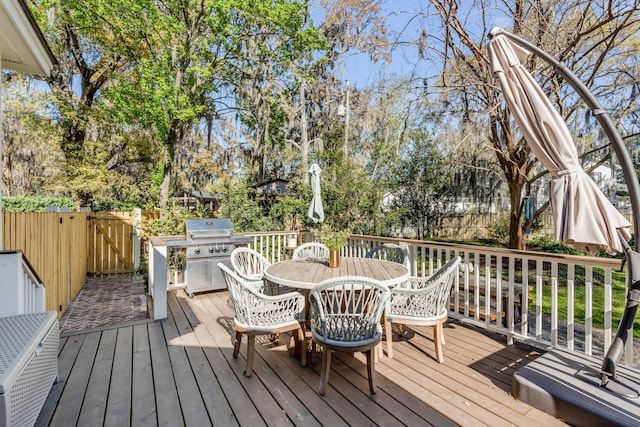 wooden terrace with outdoor dining area, a fenced backyard, and grilling area