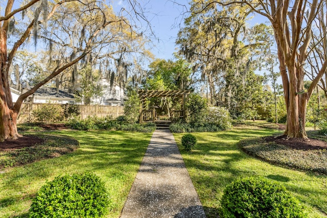 view of community with a lawn, fence, and a pergola