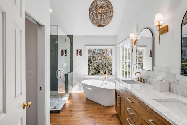 full bath with a freestanding bath, a sink, double vanity, a shower stall, and wood finished floors