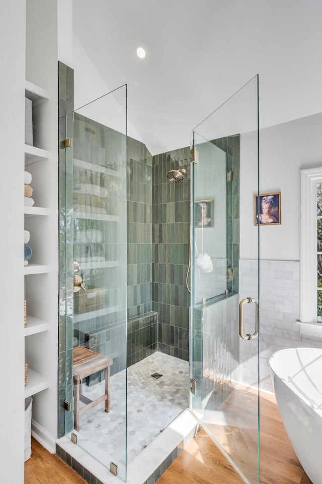 full bathroom with a soaking tub, a stall shower, and wood finished floors