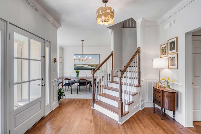 entryway with a chandelier, a healthy amount of sunlight, light wood finished floors, and a decorative wall