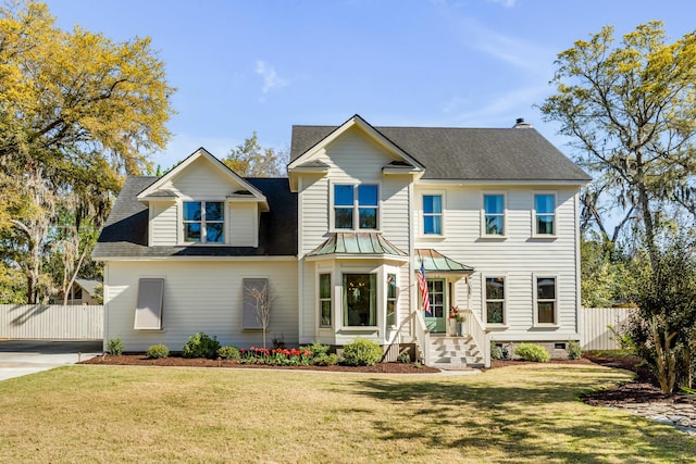 view of front of property featuring fence, roof with shingles, and a front yard
