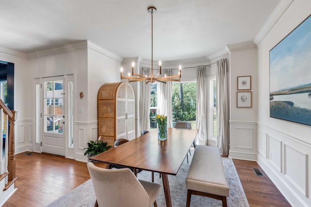 dining room with a healthy amount of sunlight, an inviting chandelier, a decorative wall, and visible vents