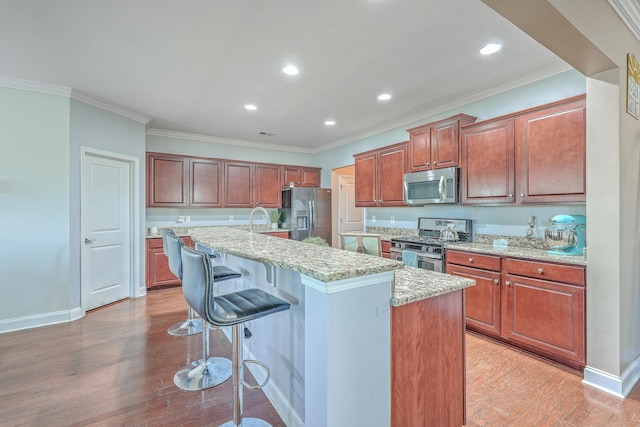 kitchen featuring a breakfast bar, light wood-style flooring, a center island with sink, and stainless steel appliances