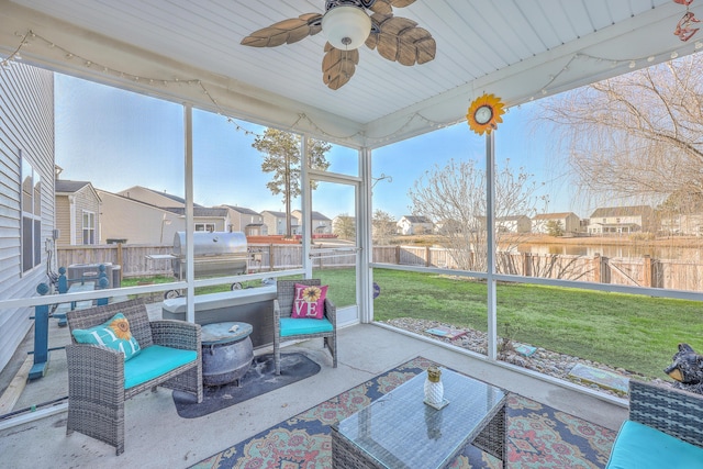 sunroom / solarium with a residential view and a ceiling fan