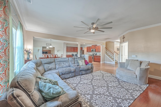 living area with stairs, ceiling fan, ornamental molding, and light wood-type flooring