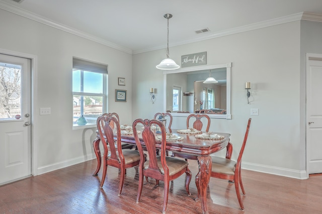 dining space featuring ornamental molding, wood-type flooring, visible vents, and baseboards