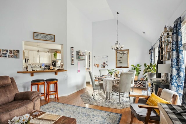 living room with baseboards, a chandelier, a wealth of natural light, wood finished floors, and high vaulted ceiling