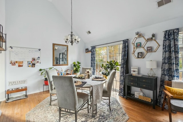 dining space featuring visible vents, an inviting chandelier, high vaulted ceiling, and light wood-style floors