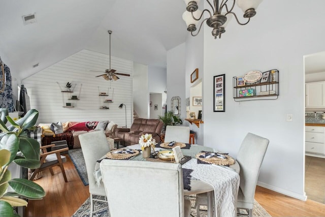 dining space with visible vents, light wood-type flooring, a ceiling fan, and vaulted ceiling