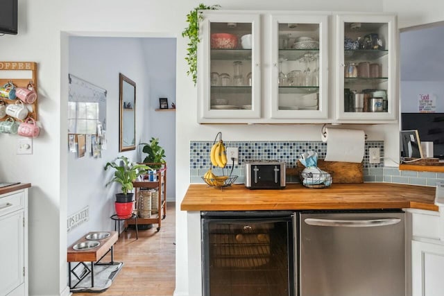 bar featuring wine cooler, light wood-style flooring, tasteful backsplash, and a bar