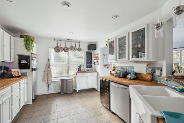 kitchen featuring tasteful backsplash, dishwasher, wood counters, and a sink