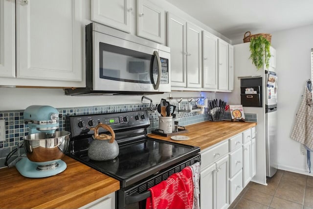 kitchen featuring tile patterned floors, black electric range, stainless steel microwave, white cabinetry, and wooden counters