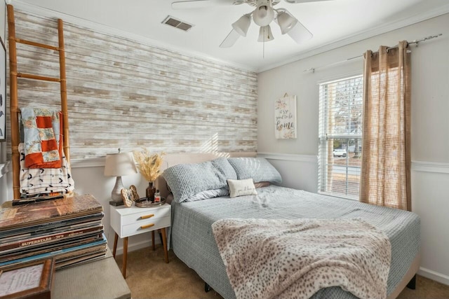 carpeted bedroom featuring visible vents, baseboards, a ceiling fan, and ornamental molding