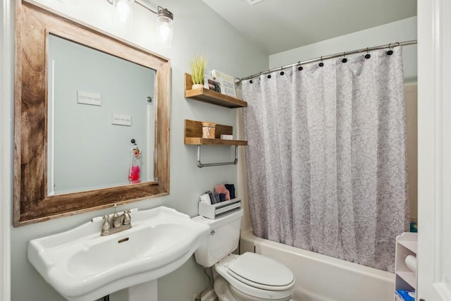 bathroom featuring a sink, toilet, and shower / tub combo with curtain