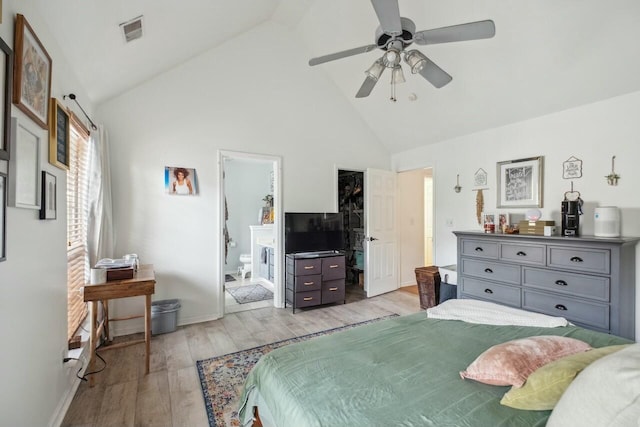 bedroom featuring light wood finished floors, visible vents, baseboards, ensuite bathroom, and high vaulted ceiling