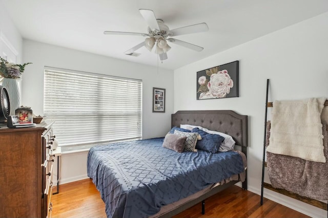 bedroom featuring a ceiling fan, visible vents, light wood finished floors, and baseboards