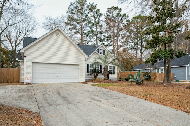 traditional home with a garage, fence, and concrete driveway