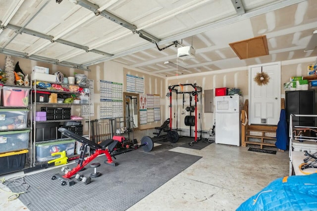 garage featuring electric panel, a garage door opener, and freestanding refrigerator