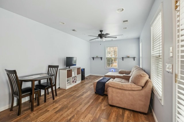 living room with ceiling fan, visible vents, baseboards, and wood finished floors