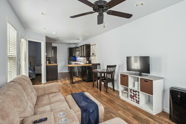 living area featuring a ceiling fan, recessed lighting, wood finished floors, and baseboards