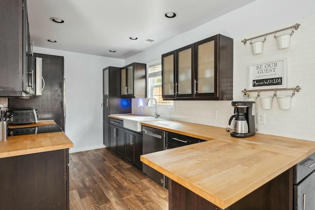 kitchen featuring a sink, tasteful backsplash, dark wood-style flooring, and butcher block counters