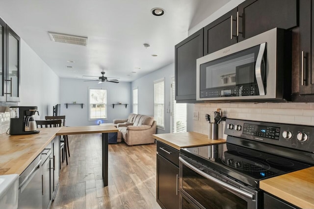 kitchen with visible vents, decorative backsplash, appliances with stainless steel finishes, and butcher block counters