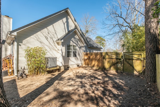 back of house with crawl space, a gate, fence, and a chimney