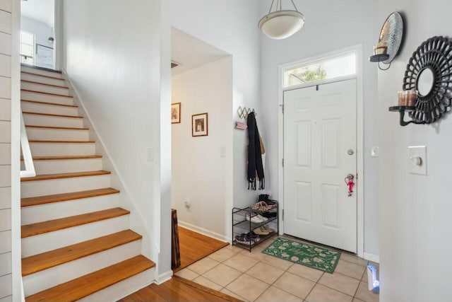 foyer featuring light tile patterned floors, stairway, baseboards, and a healthy amount of sunlight